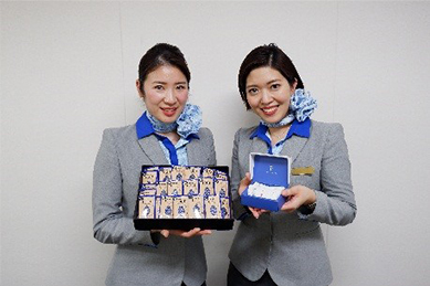 写真：ANAオリジナルデザイン 「明治 ザ・チョコレートコンフォートビター」を持つ客室乗務員